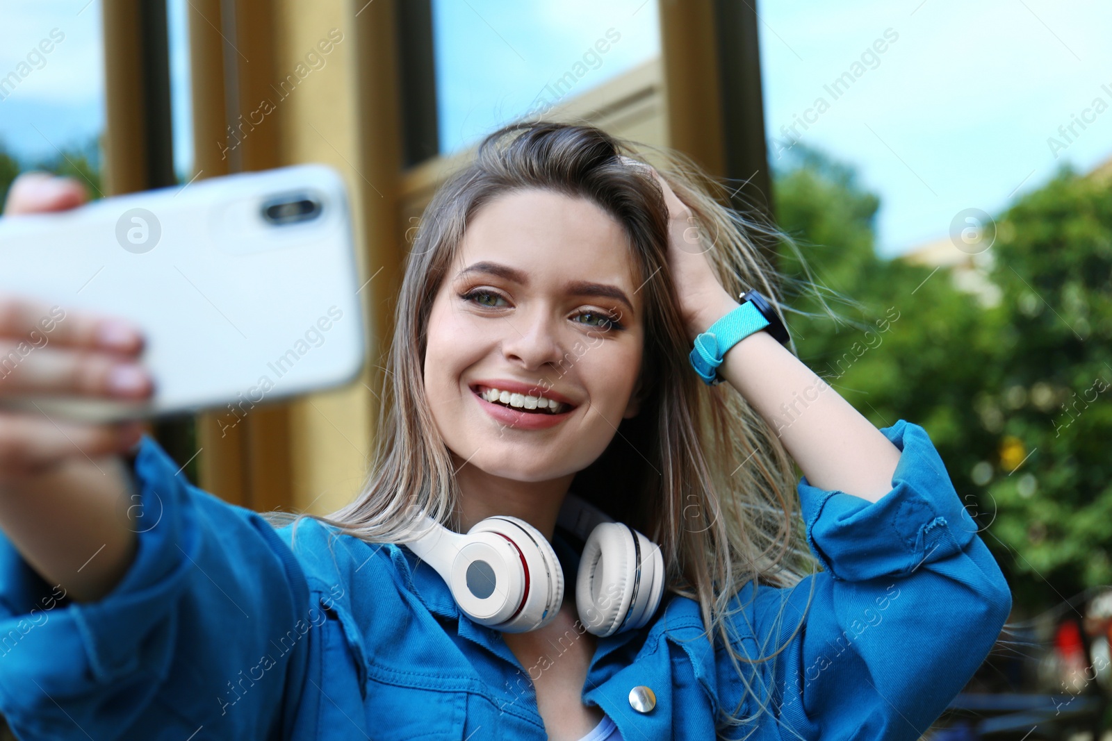 Photo of Happy young woman taking selfie on city street