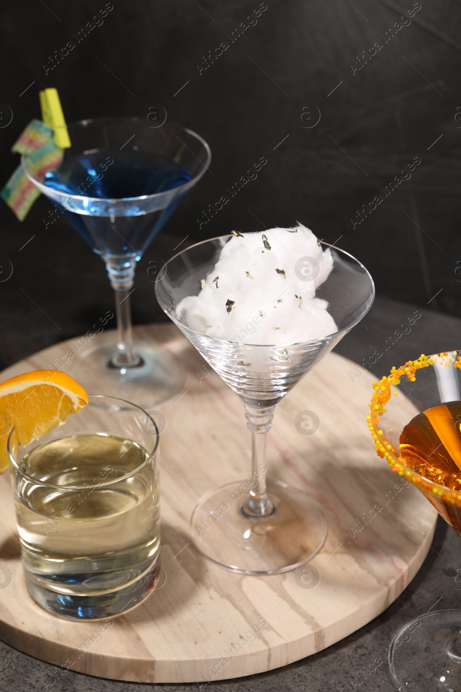 Photo of Tasty cotton candy cocktail and other alcoholic drinks in glasses on gray textured table