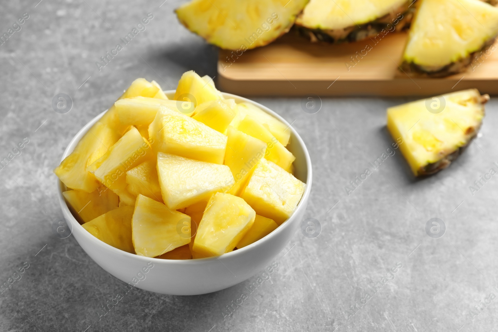 Photo of Bowl with fresh pineapple slices on grey background