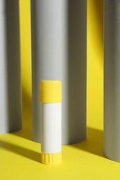 Photo of Glue stick near paper rolls on yellow background
