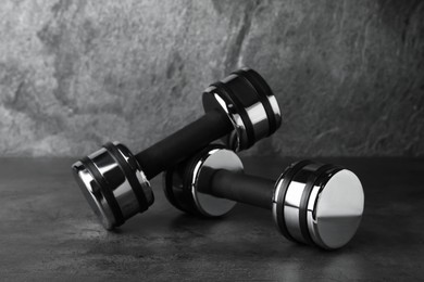 Photo of Metal dumbbells on table against grey background