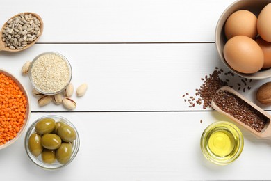 Photo of Different products high in natural fats on white wooden table, flat lay. Space for text