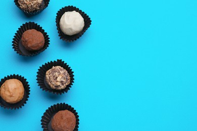 Photo of Tasty chocolate candies on light blue background, flat lay. Space for text
