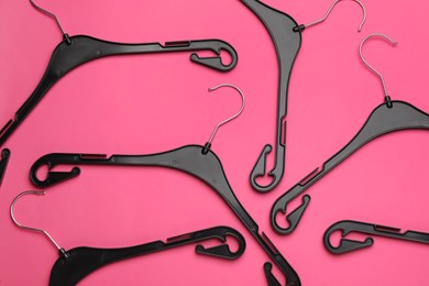 Photo of Empty hangers on pink background, flat lay