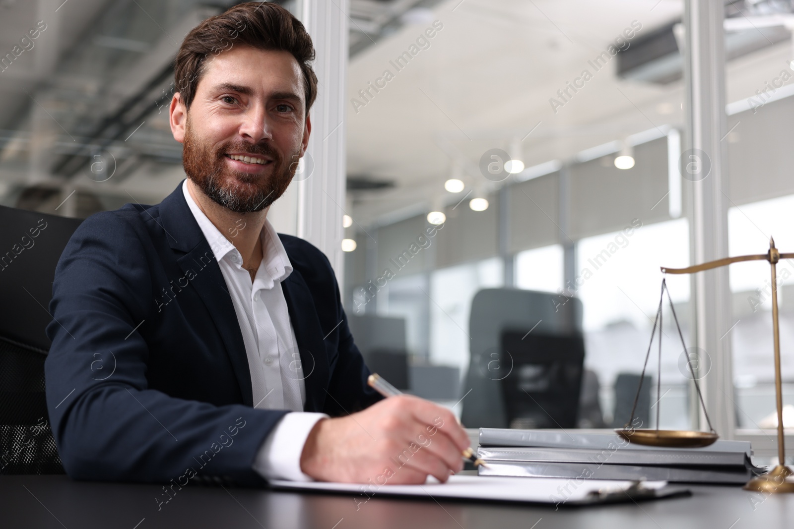Photo of Portrait of smiling lawyer at table in office. Space for text
