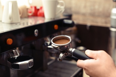 Photo of Male barista making espresso using professional coffee machine, closeup