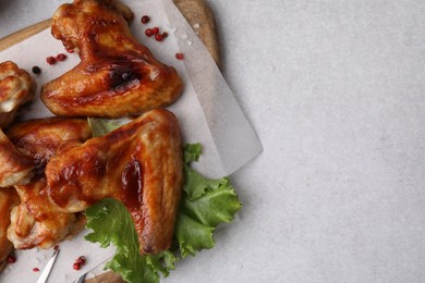 Photo of Fresh marinated chicken wings and lettuce on light table, top view. Space for text