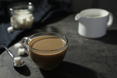 Photo of Tasty coffee with milk in cup and sugar cubes on grey table, closeup