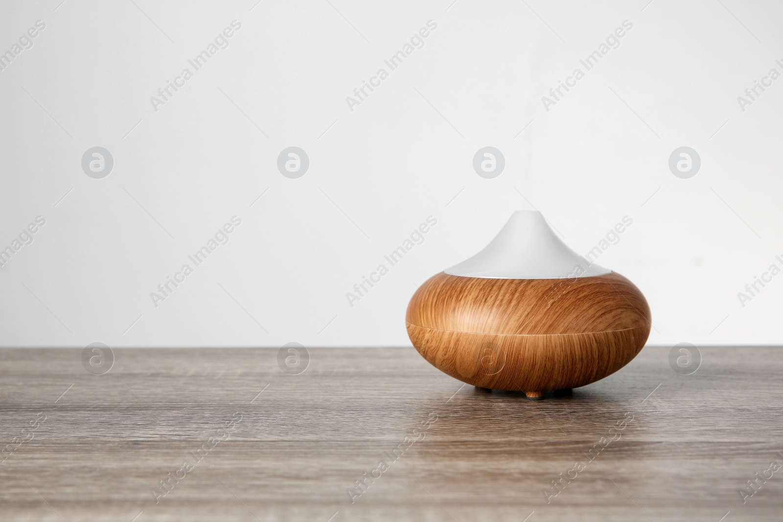 Photo of Aroma oil diffuser lamp on table against light background