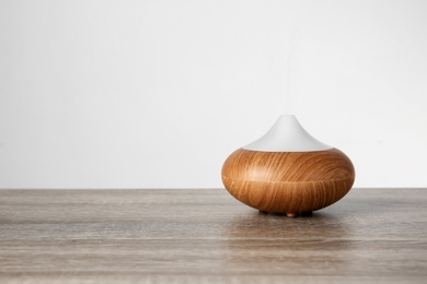 Photo of Aroma oil diffuser lamp on table against light background