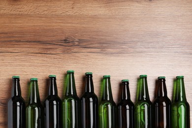 Bottles of tasty beer on wooden table, flat lay. Space for text
