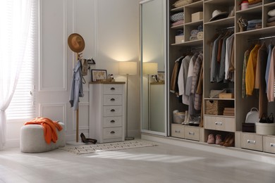 Photo of Wardrobe closet with different stylish clothes, shoes and home stuff in room