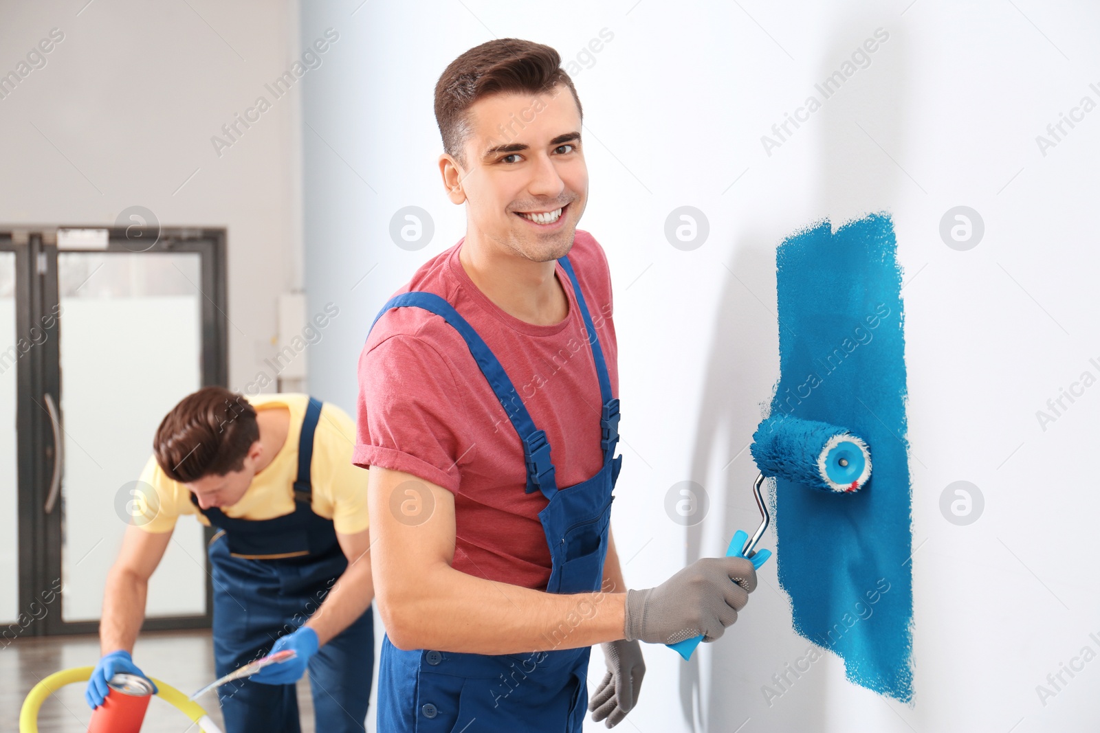 Photo of Male decorator painting wall with roller indoors