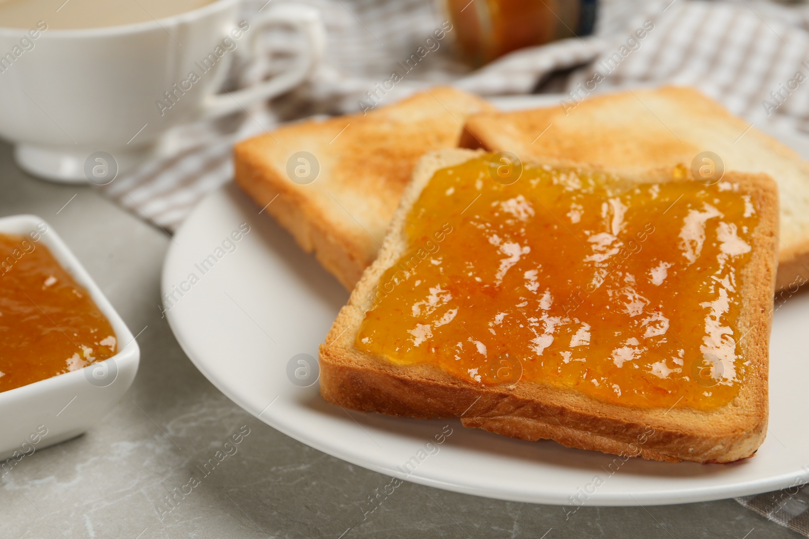 Photo of Toast with tasty orange jam and roasted slices of bread on table, closeup