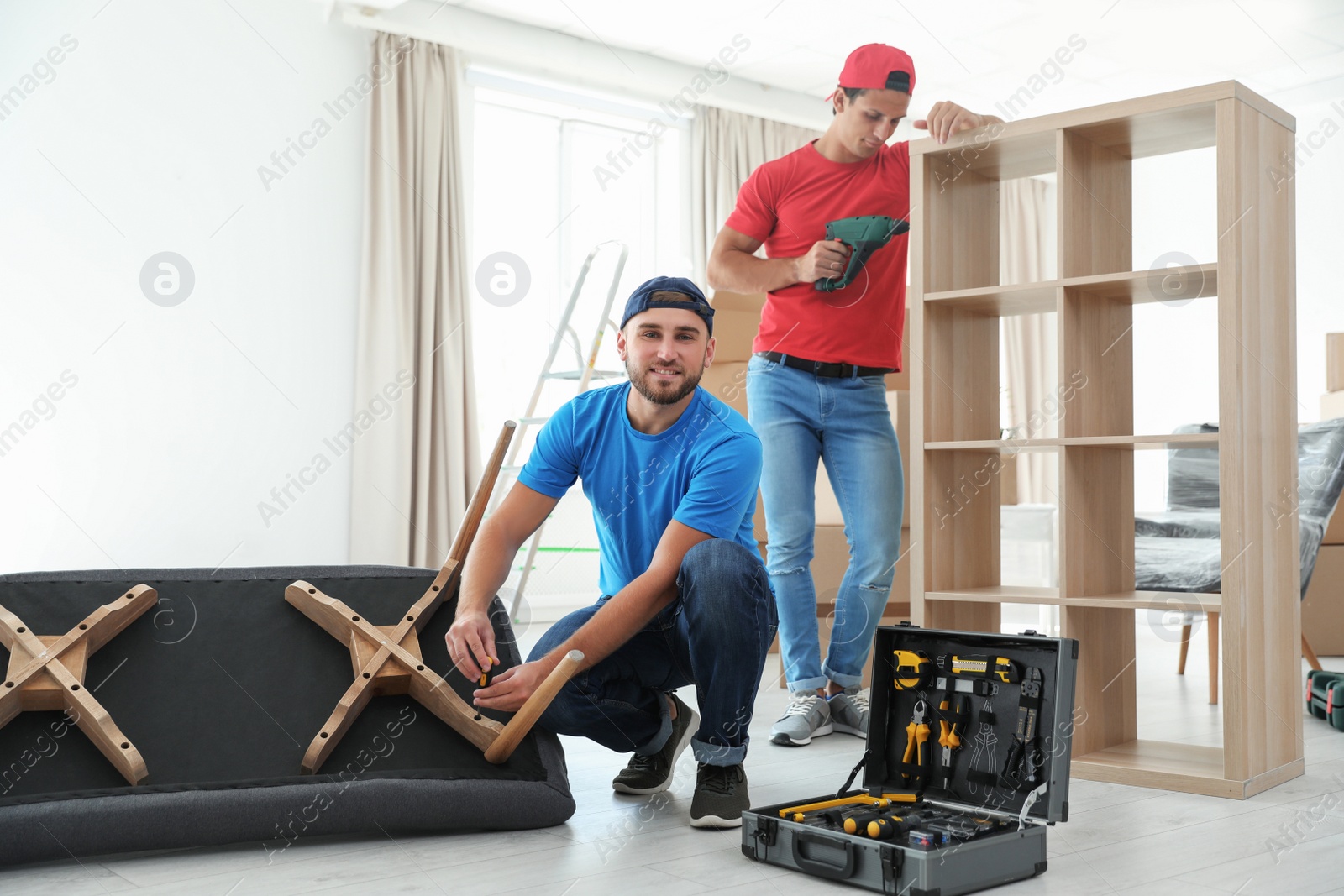 Photo of Male movers assembling furniture in new house