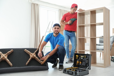 Photo of Male movers assembling furniture in new house