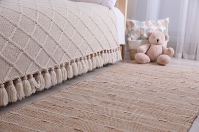 Photo of Stylish children's room interior with beige rug and bed