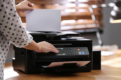 Photo of Employee using modern printer in office, closeup