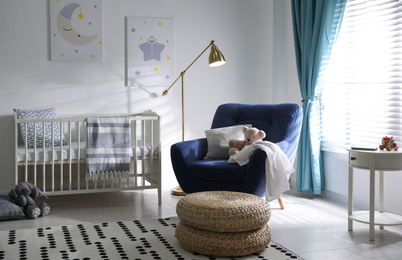 Photo of Cozy baby room interior with comfortable armchair