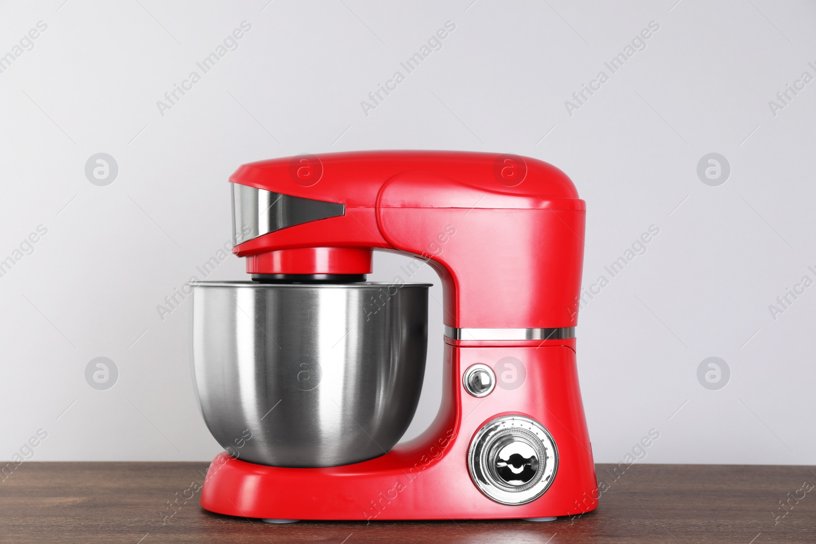 Photo of Modern red stand mixer on wooden table against gray background