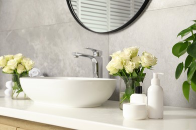 Beautiful roses and bath accessories near sink in bathroom