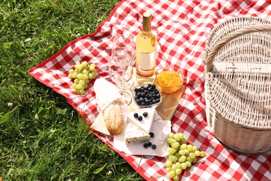 Photo of Picnic blanket with delicious food and wine outdoors on summer day