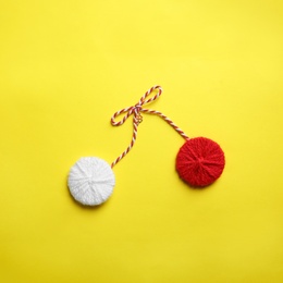 Photo of Traditional martisor on yellow background, top view. Beginning of spring celebration