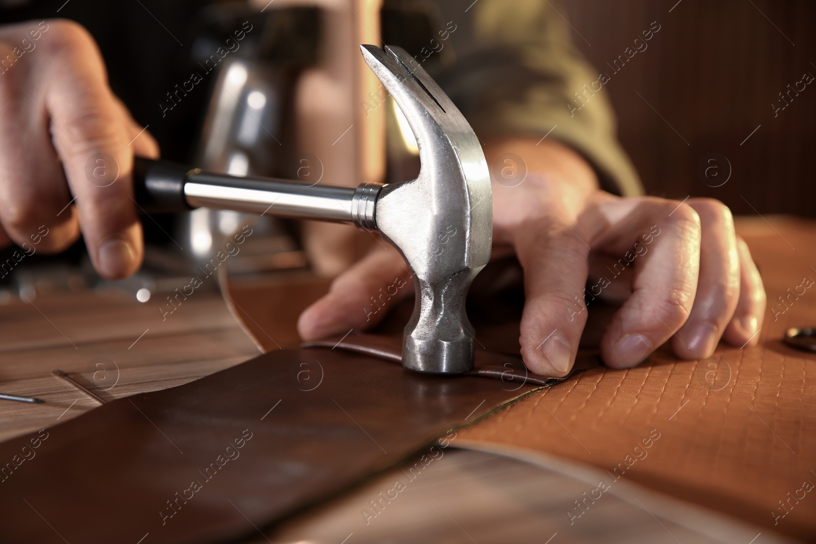 Photo of Man working with piece of leather at table, closeup