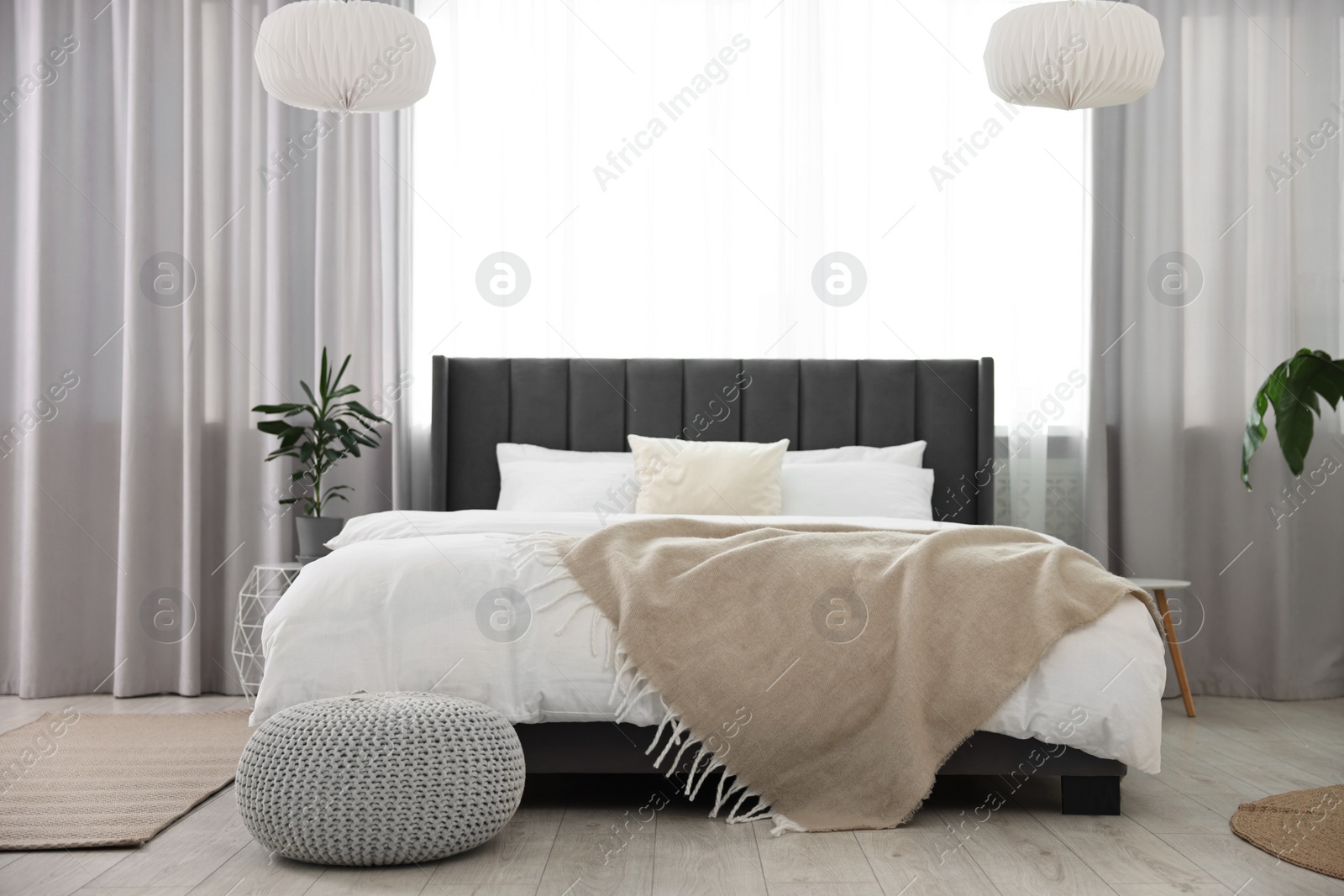 Photo of Soft beige plaid on bed in stylish bedroom. Interior design