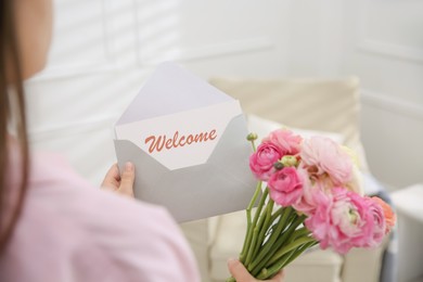 Image of Welcome card. Woman holding envelope and ranunculus flowers on indoors, closeup