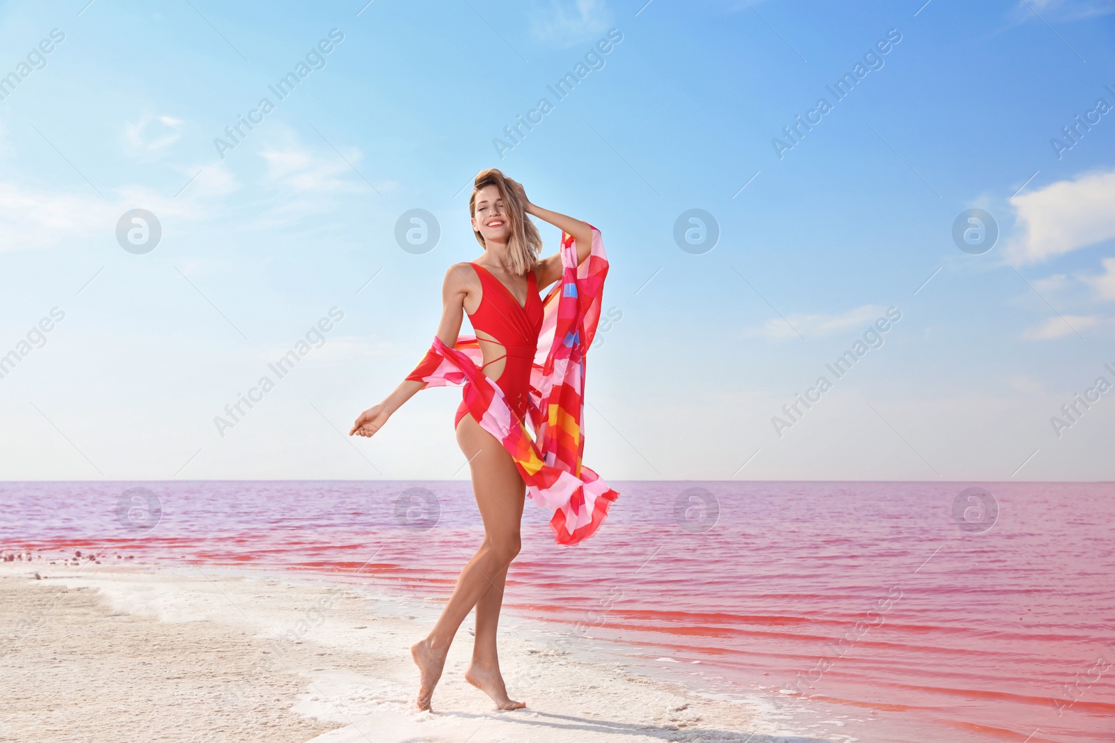 Photo of Beautiful woman in swimsuit posing near pink lake on sunny day