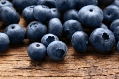 Photo of Many tasty fresh blueberries on wooden table, closeup