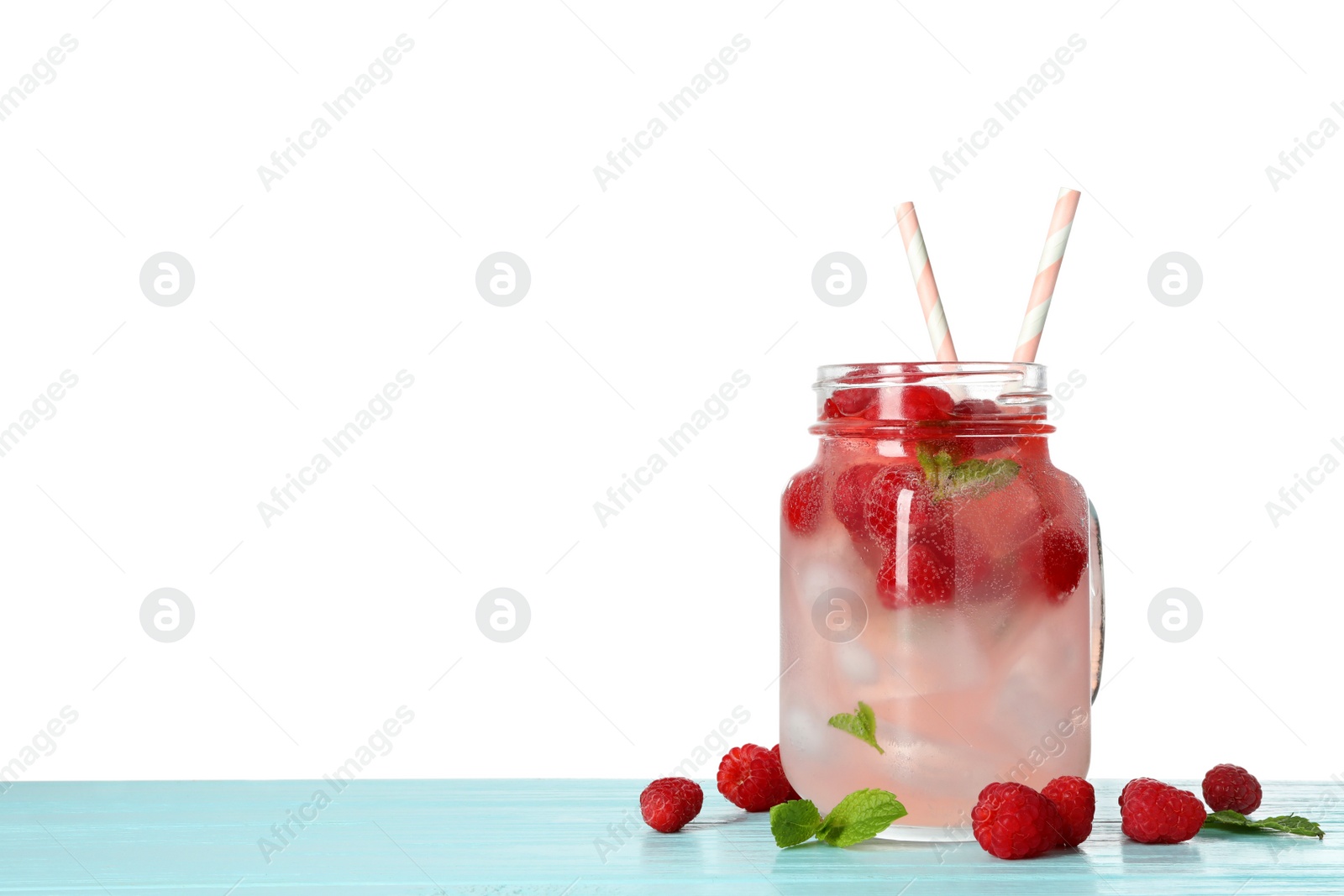 Photo of Mason jar with raspberry refreshing drink on blue wooden table against white background