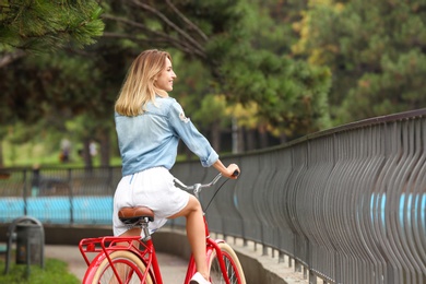 Beautiful woman in casual outfit with bicycle outdoors. Space for text