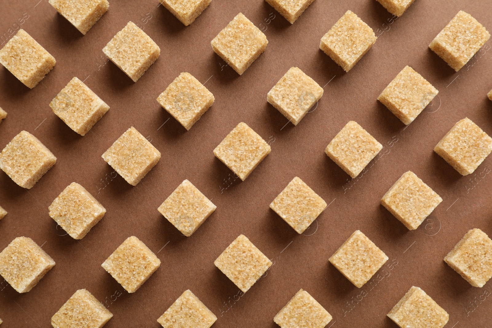 Photo of Brown sugar cubes on color background, top view