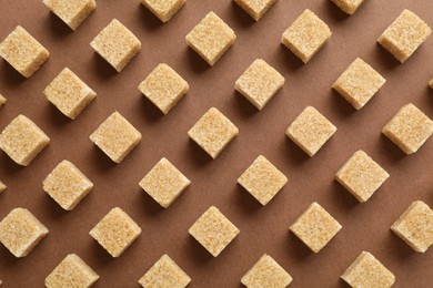 Brown sugar cubes on color background, top view