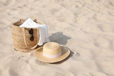 Beach bag, towel, sunglasses and hat on sand, space for text