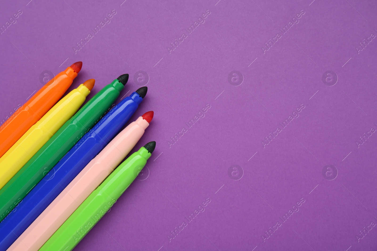 Photo of Different colorful markers on purple background, flat lay. Space for text