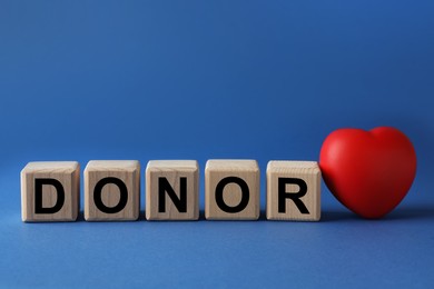 Wooden cubes with word Donor and small red heart on blue background