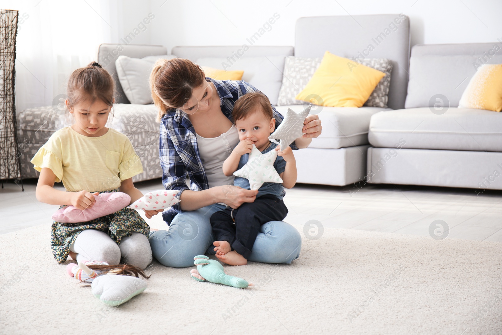 Photo of Mother with cute little children sitting on cozy carpet at home