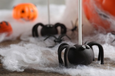 Photo of Spider shaped cake pops on wooden table, closeup. Halloween treat