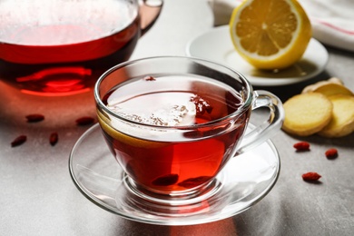 Photo of Glass cup of healthy goji tea with lemon on grey table