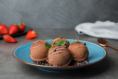 Photo of Plate of chocolate ice cream with mint on grey table, space for text