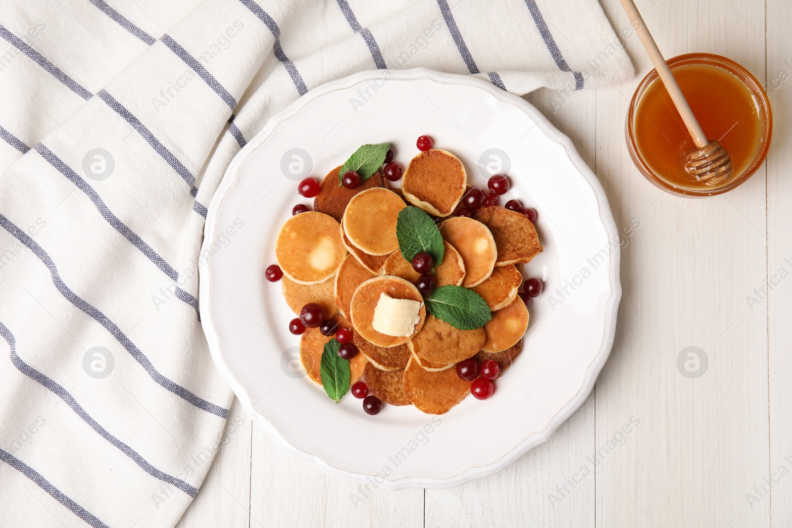 Photo of Cereal pancakes with cranberries and butter on white wooden table, flat lay
