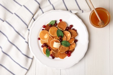 Photo of Cereal pancakes with cranberries and butter on white wooden table, flat lay