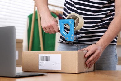 Photo of Seller taping parcel at workplace, closeup. Online store