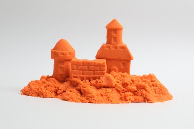 Photo of Castle figures made of orange kinetic sand isolated on white