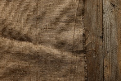 Burlap fabric on wooden table, top view