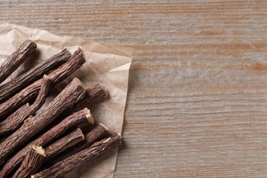 Photo of Dried sticks of liquorice root on wooden table, top view. Space for text