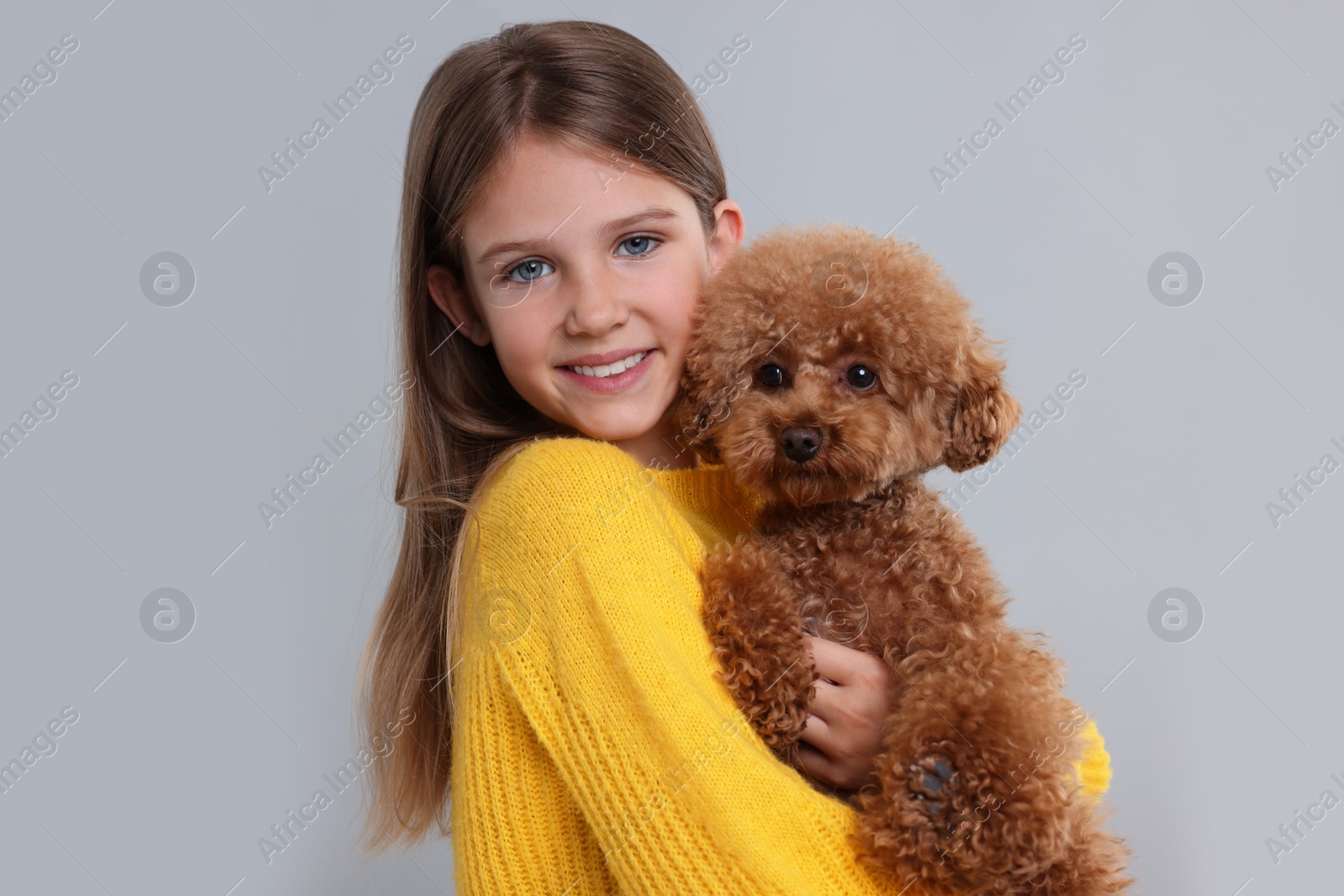 Photo of Little child with cute puppy on light grey background. Lovely pet